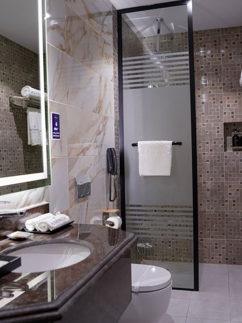 Deluxe Room bathroom with a shower, toilet, and sink at Warwick Hotel & Spa - Jeddah.