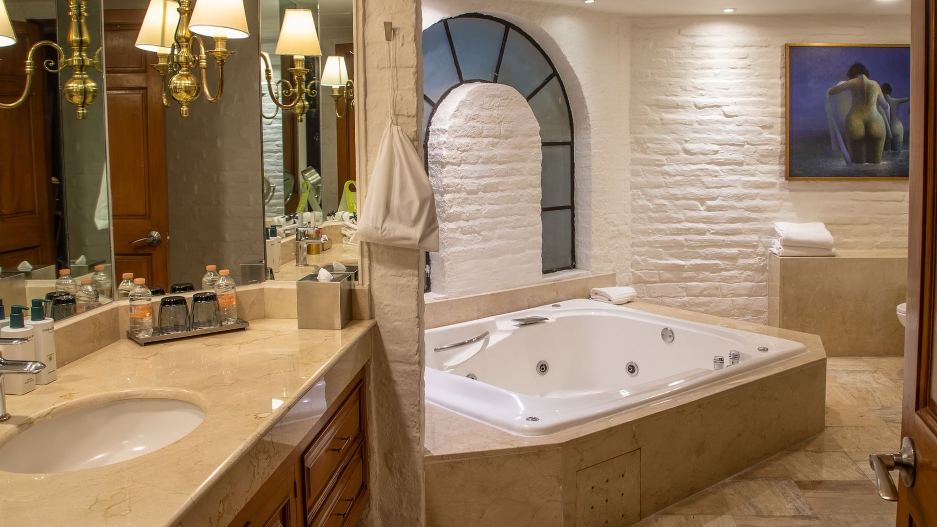 Baño elegante con jacuzzi, paredes de piedra blanca y arco decorativo en Suite Presidencial King en Quinta Real Guadalajara