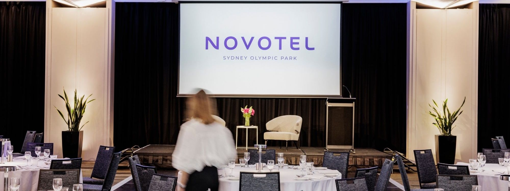 Set up banquets facing the stage screen in Freshwater Ballroom at Novotel Sydney Olympic Park