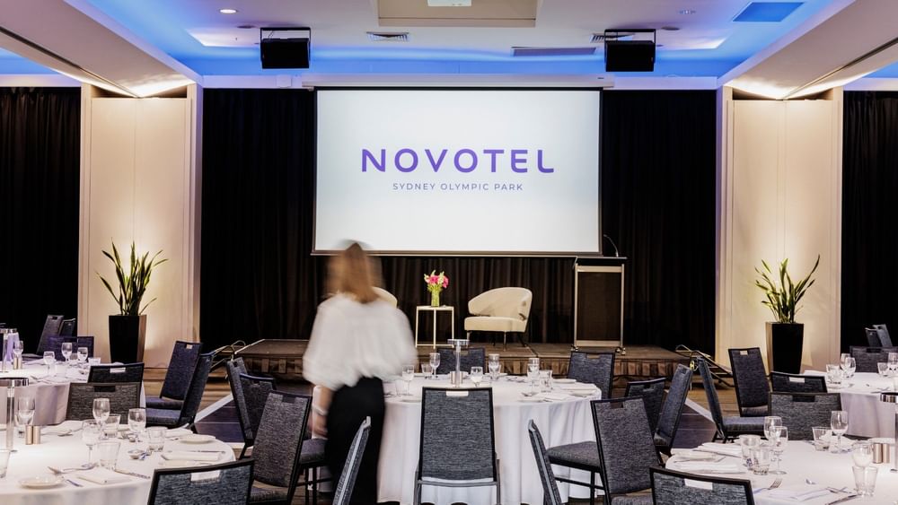 Set up banquets facing the stage screen in Freshwater Ballroom at Novotel Sydney Olympic Park