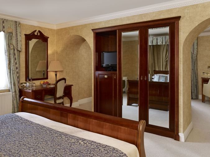 Beautifully decorated Brampton Lodge Suite at Marygreen Manor, featuring a large bed, cozy desk, and mirrored wardrobe doors