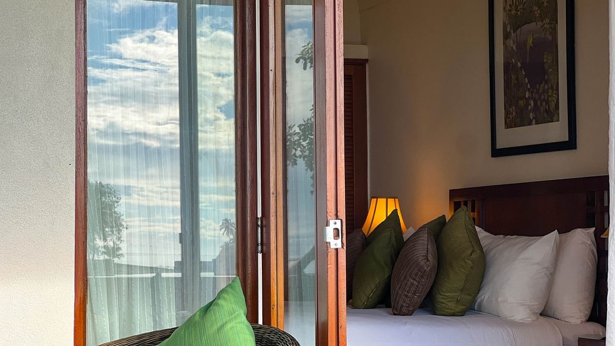 View of a cozy bedroom with large bed and wicker chair at The Naviti Resort in Korolevu, Fiji.