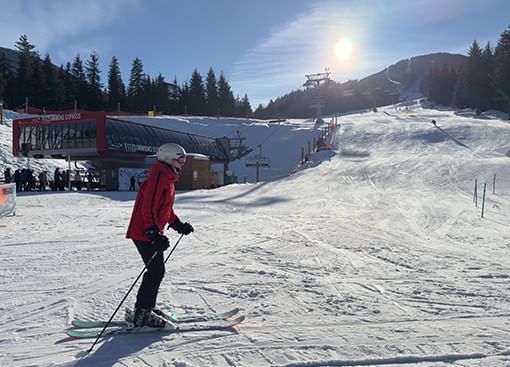 Skier in a red jacket enjoying a sunny winter day on a snow-covered ski slope in Blackcomb Ski Resort