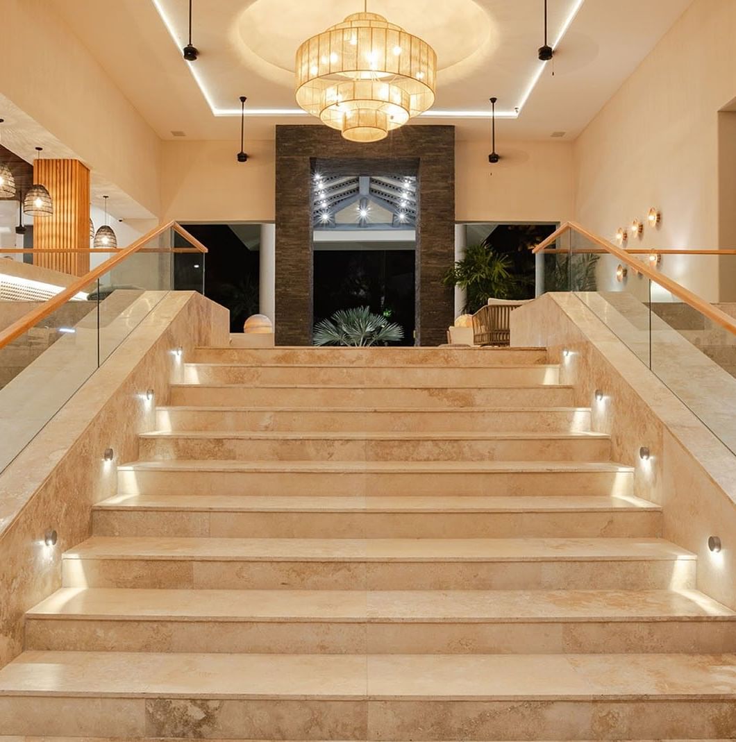 Luxury lobby lounge area featuring a grand stone staircase and an elegant chandelier at Camino Real Acapulco Diamante
