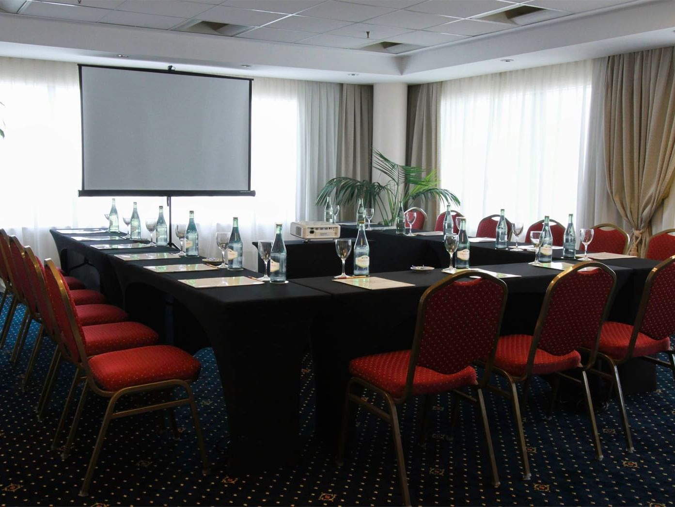 Aranjuez meeting room arranged with tables and red chairs at Hotel Emperador Buenos Aires