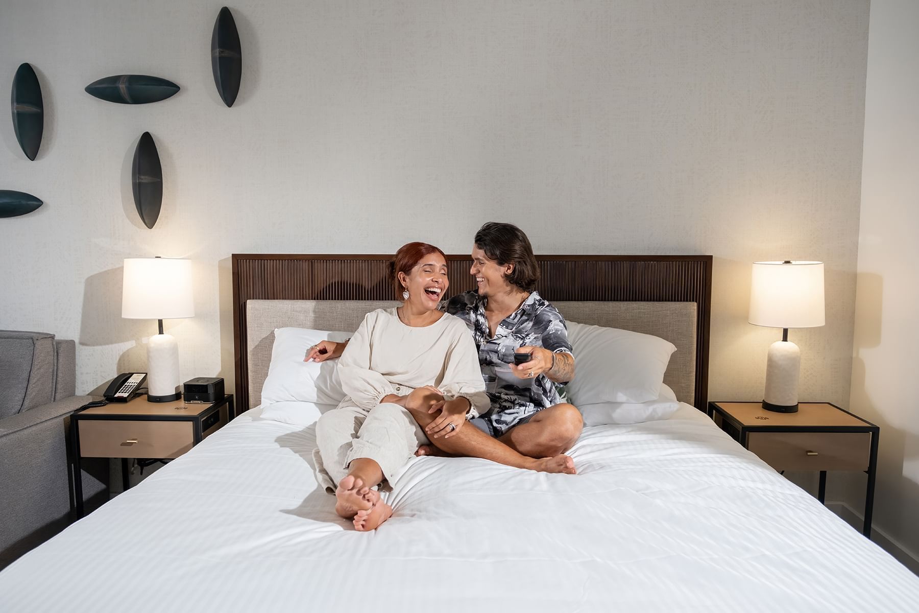 Two people sitting on a bed in a hotel room