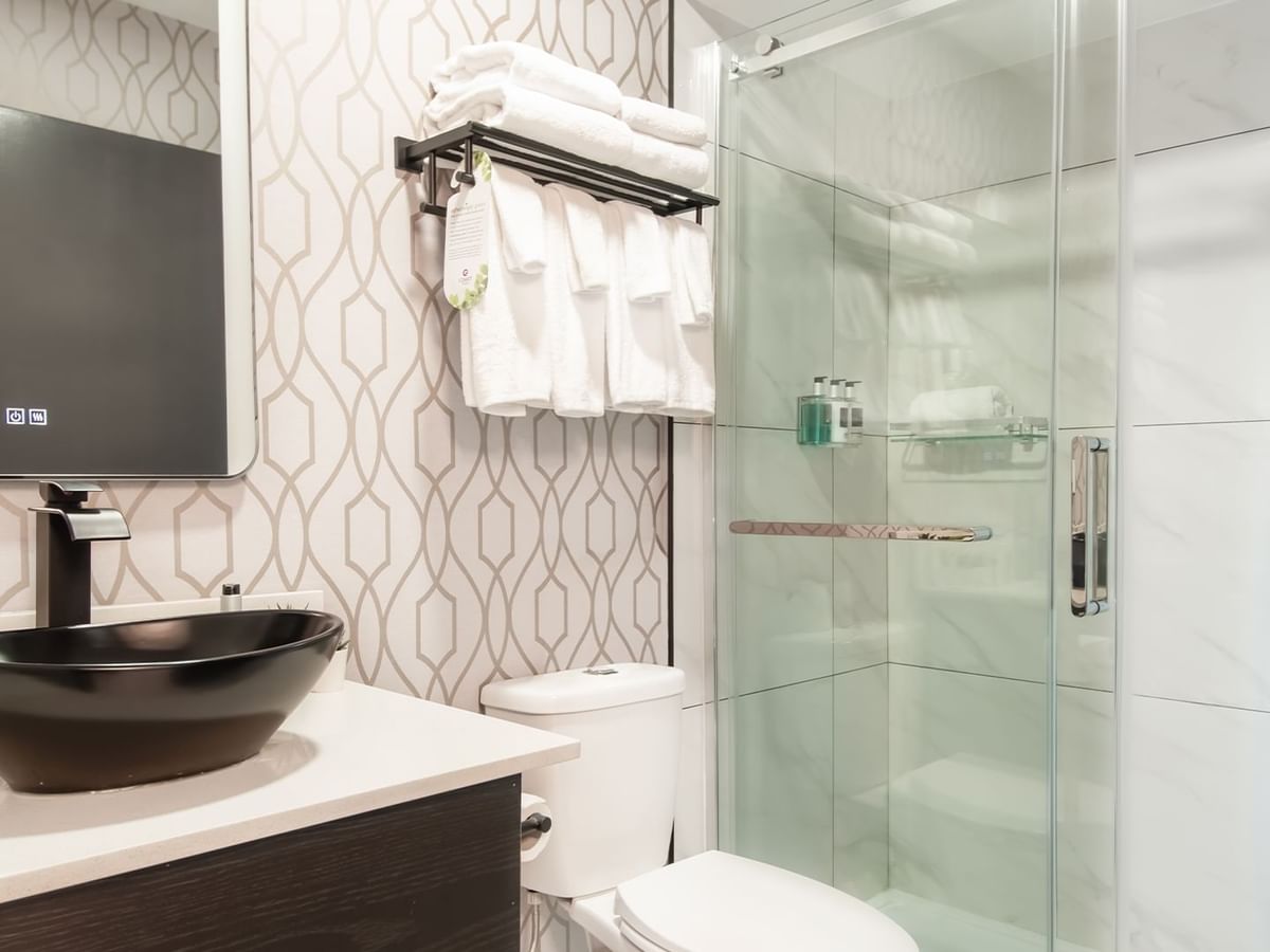 Bathroom with shower, toilet, sink, mirror, towels and soap