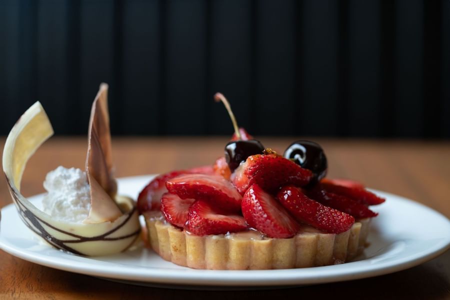 Dessert tart topped with glossy sliced strawberries and cherries in Artist Lobby Lounge at Warwick Hotel Jeddah