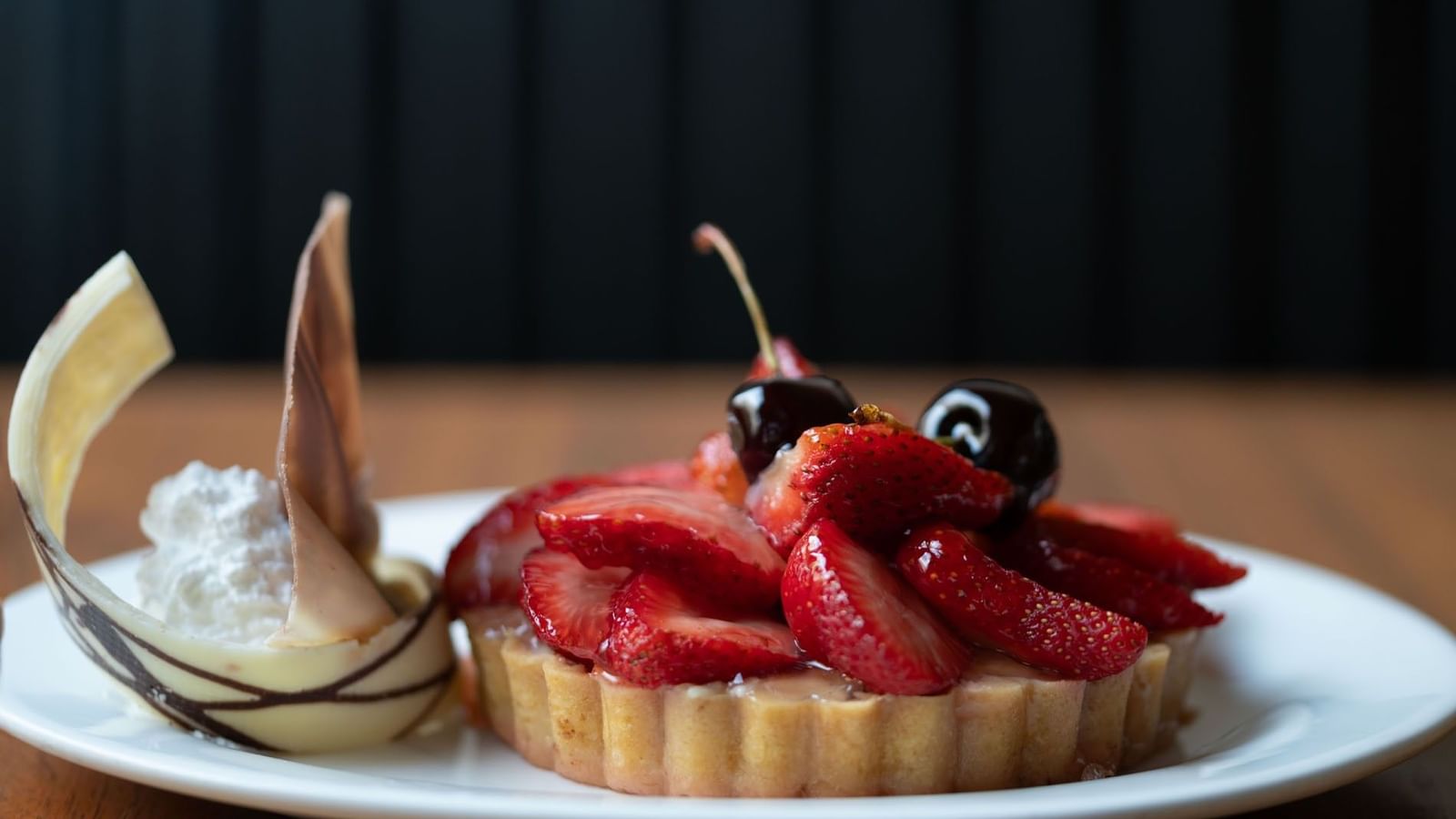 Dessert tart topped with glossy sliced strawberries and cherries in Artist Lobby Lounge at Warwick Hotel Jeddah