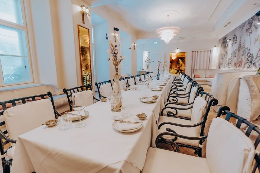 Long set table decorated with dried flowers and black curved chairs in private hall