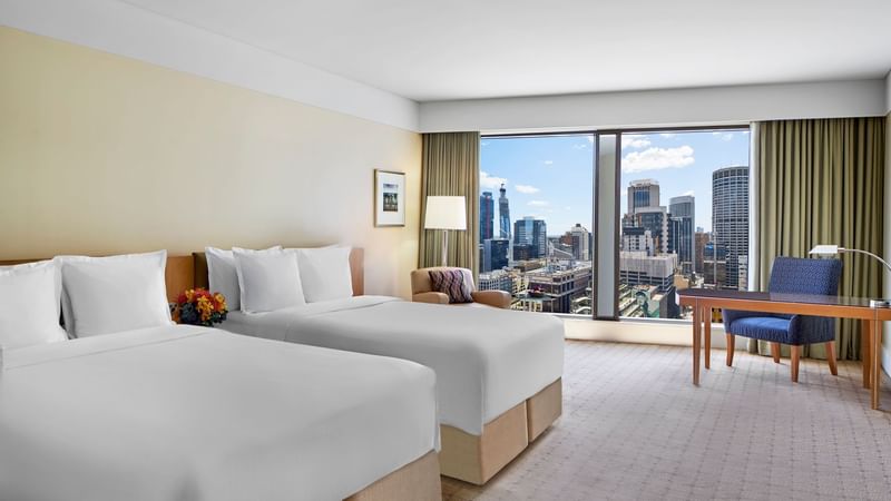 Tower deluxe twin room with two beds overlooking the city through a large window at The Fullerton Hotel Sydney