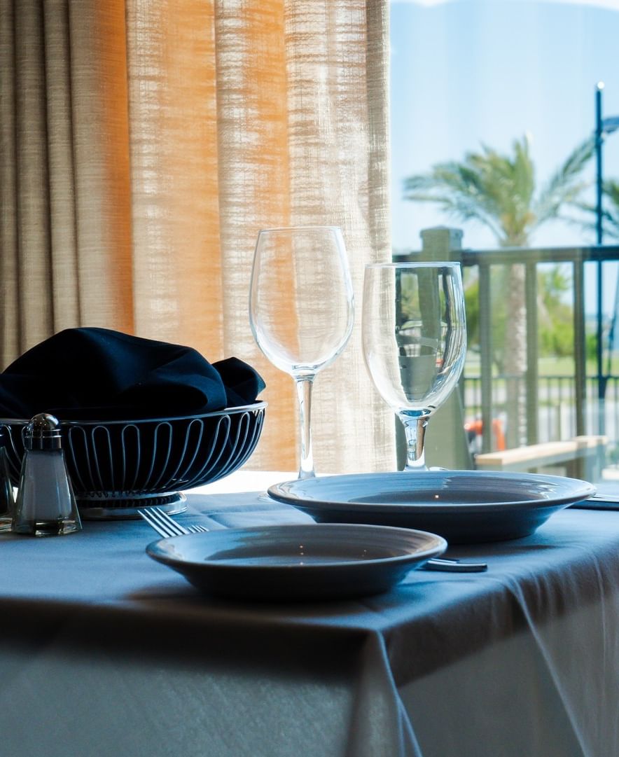 The Library restaurant table setting with wine glasses near a window with sheer curtains at The Markham Hotel