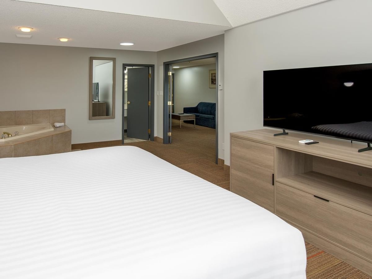 Coast Suite with white bed, jetted tub, flat-screen TV, and separate living area.