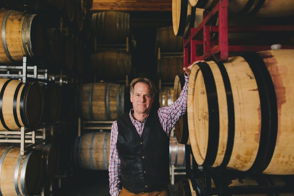 Man leaning against wine barrel 