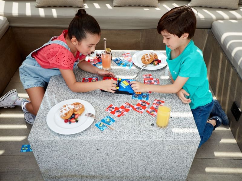 Two children happily playing with a puzzle on a table at Fiesta Americana