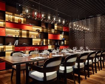 Square One’s dining area featuring a wooden table, sleek chairs, and a lively artistic wall at Park Hyatt Saigon