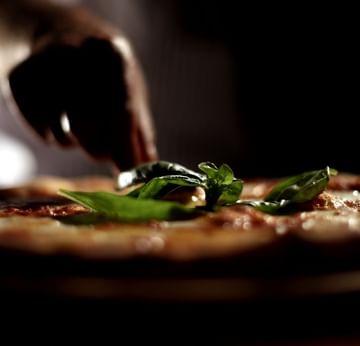 Hand garnishing pizza with basils in Sapore Italian Snack at Titanic Deluxe Lara