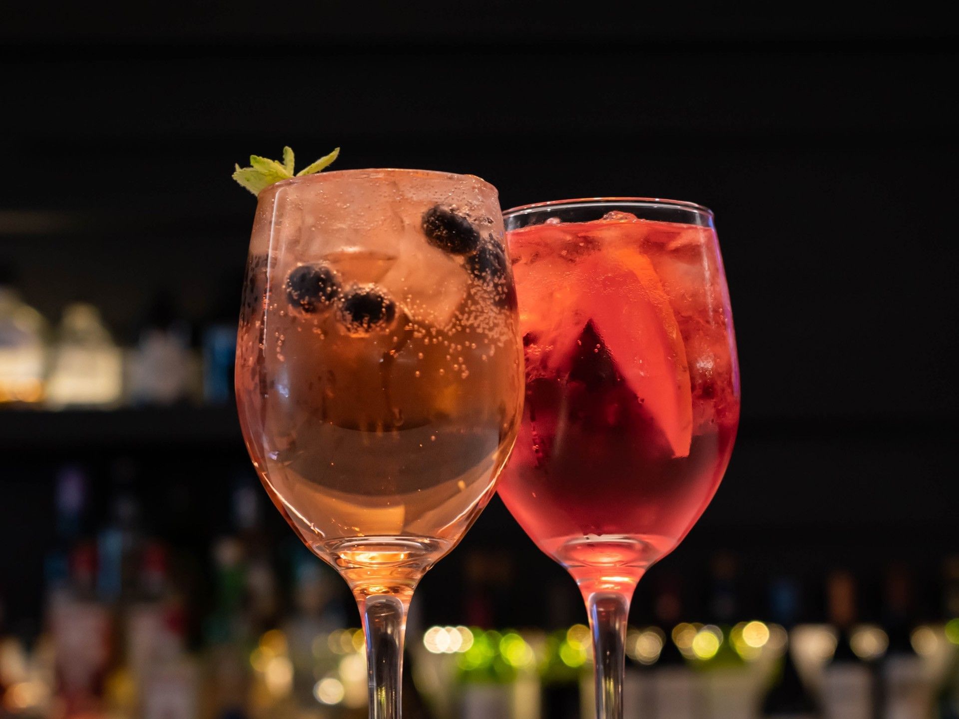 Dos copas de vino llenas de bebida y adornos sobre la barra de un bar.