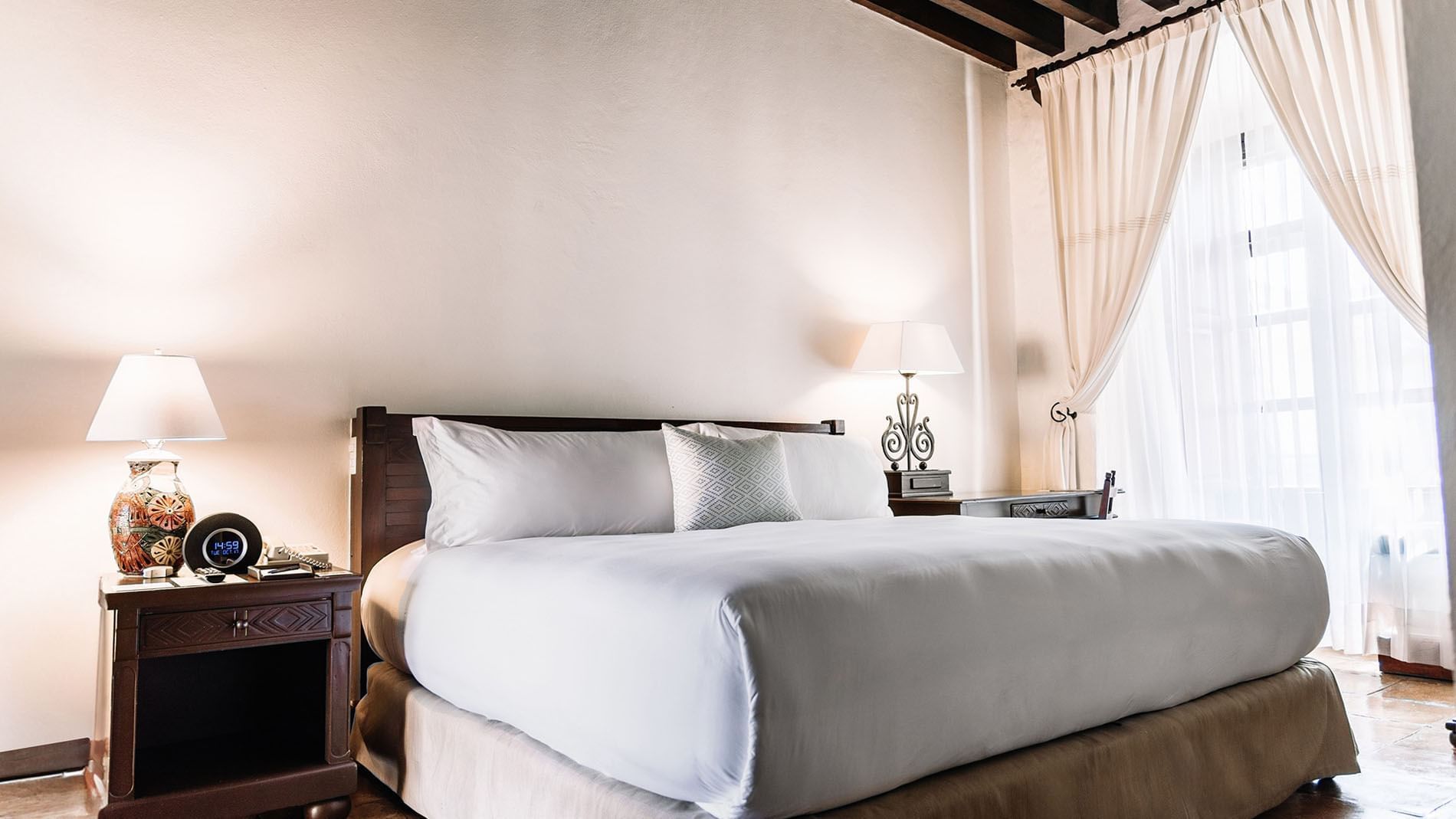 Nightstand and workspace by the bed with plush pillows in the King Grand Class Suite at Quinta Real Oaxaca