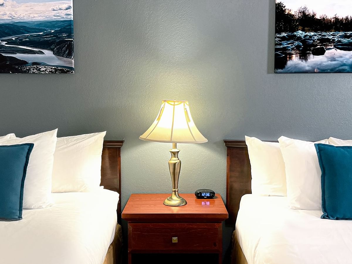 Hotel bedroom with two beds, night stand, lamp, and paintings