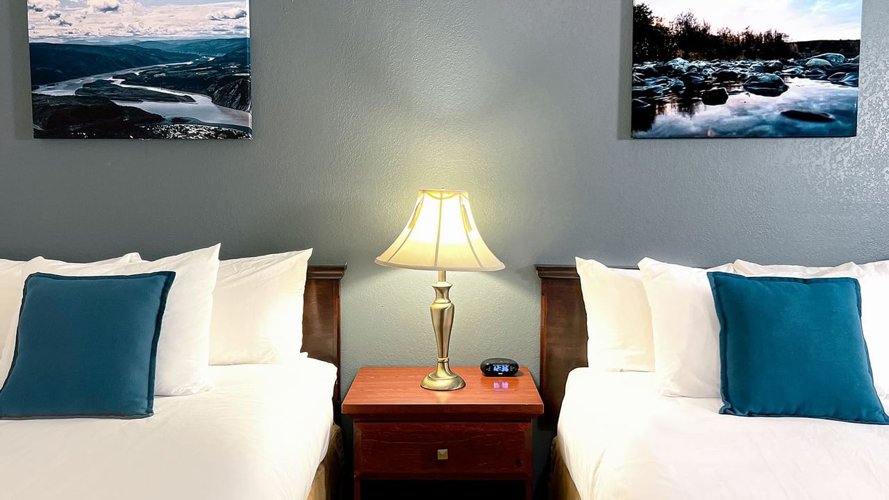 Hotel bedroom with two beds, night stand, lamp, and paintings