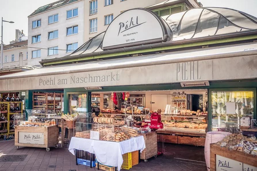 Pöhl at Vienna Naschmarkt with delicatessen products, bread and specialties displayed in front of the market stall