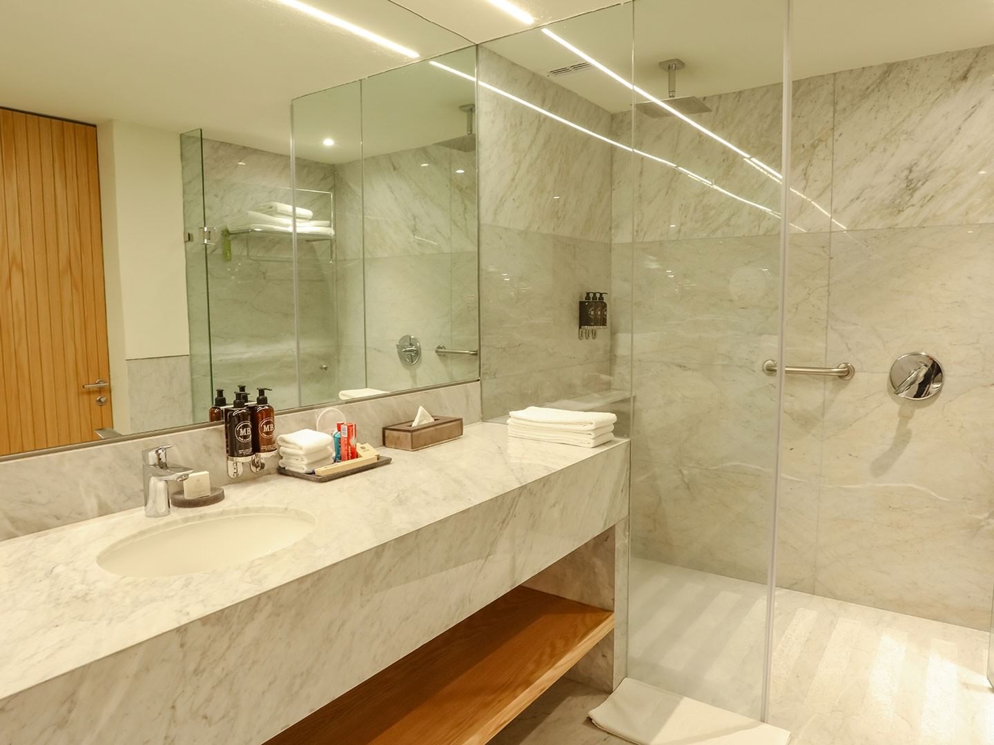 Bathroom with marble sink, large mirror, glass shower, and toiletries at Camino Real Polanco Mexico in Ciudad de Mexico.