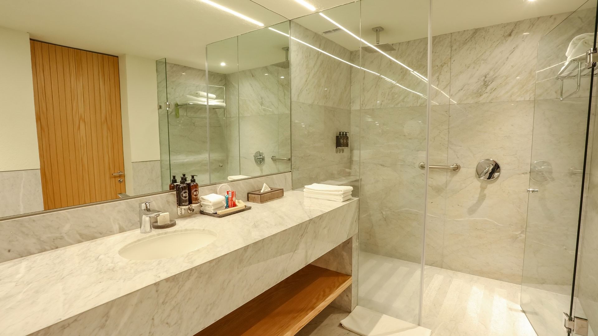 Bathroom with marble sink, large mirror, glass shower, and toiletries at Camino Real Polanco Mexico in Ciudad de Mexico.