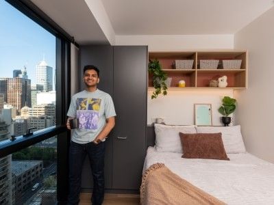 Young man standing in a furnished student apartment in Melbourne city.