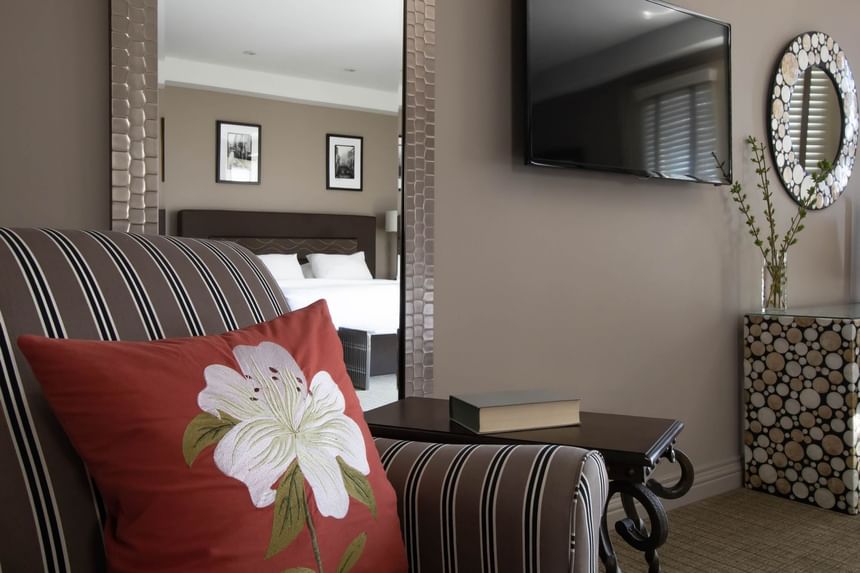 TV & comfy chair with a red accent pillow in the living area of King Superior Den at Retro Suites Hotel