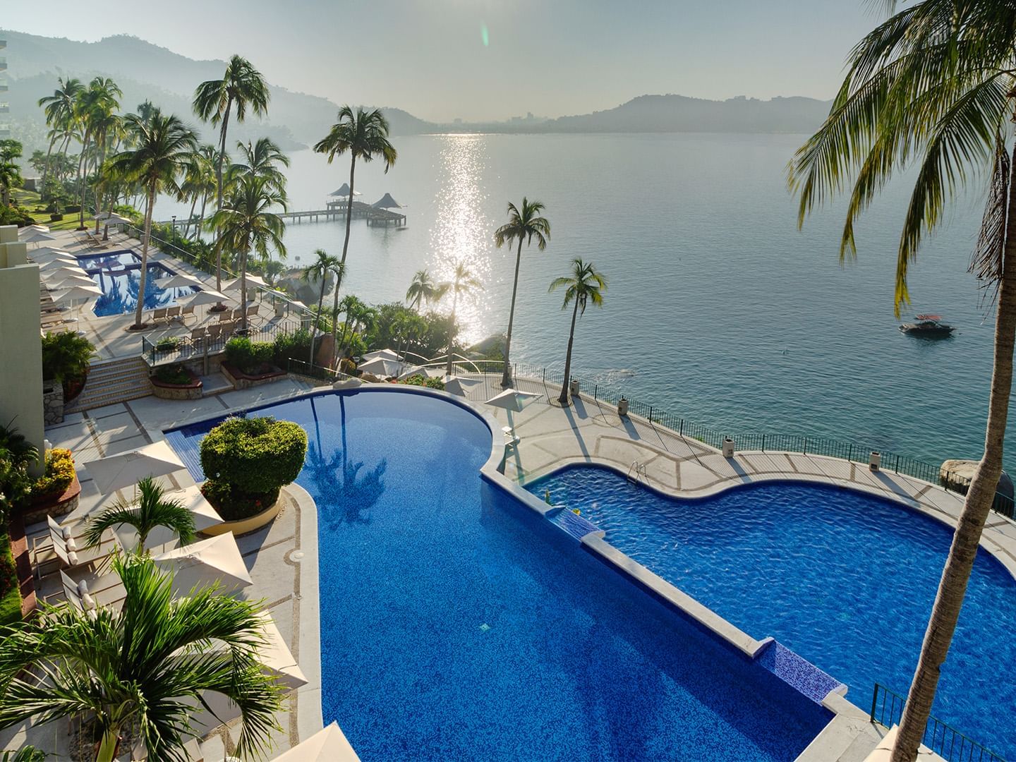 Luxury infinity pool overlooking a sparkling ocean bay during a bright day at Camino Real Acapulco Diamante