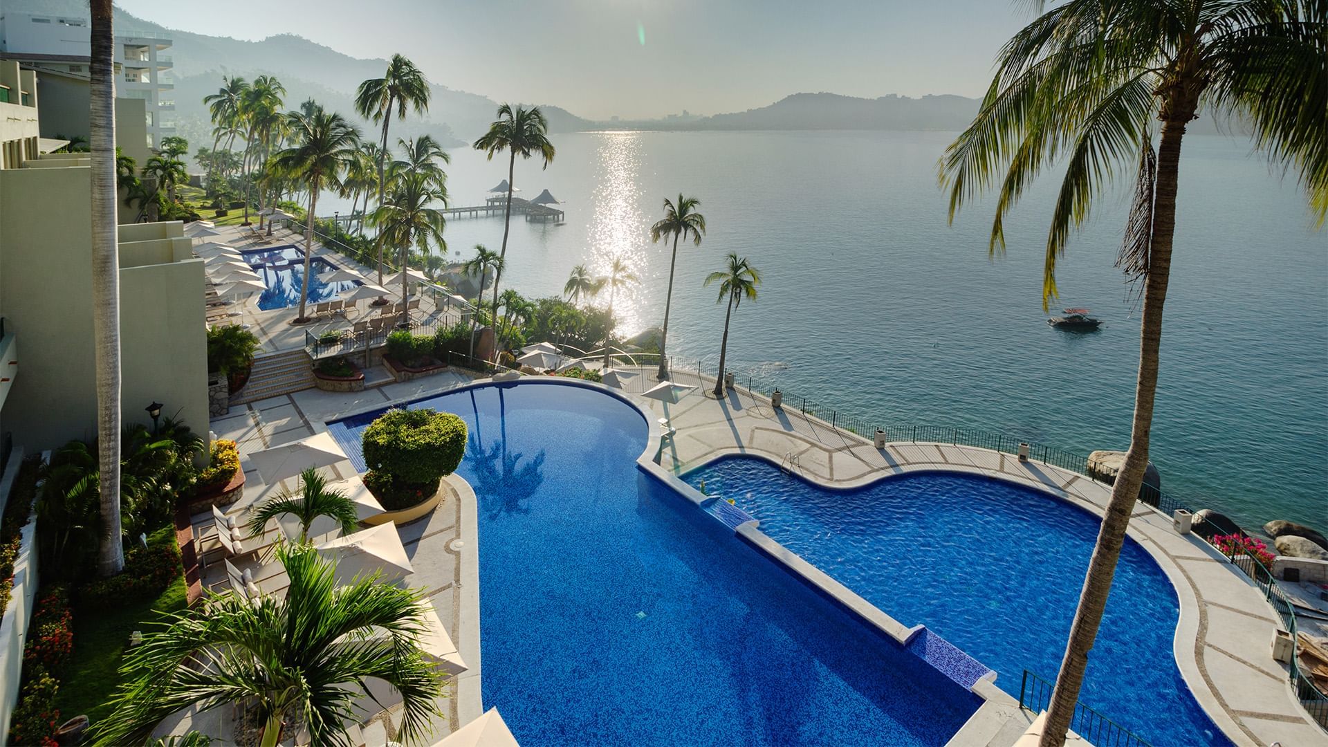 Luxury infinity pool overlooking a sparkling ocean bay during a bright day at Camino Real Acapulco Diamante
