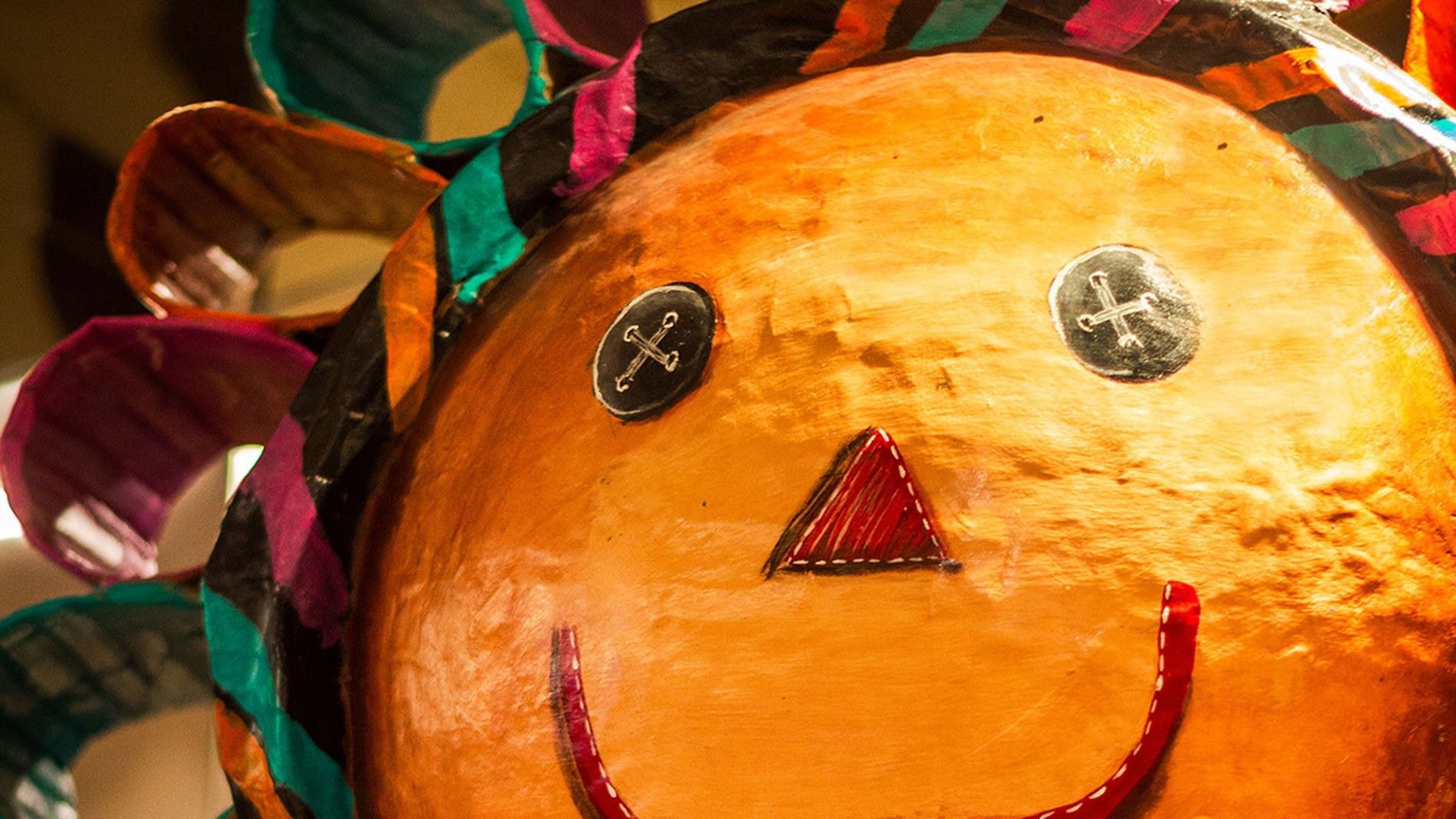 Close-up of a colorful, handcrafted sun face decoration with button eyes at Camino Real Aeropuerto Mexio