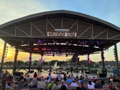 A performance at the AdventHealth Waterside Stage at Disney Springs at sunset.