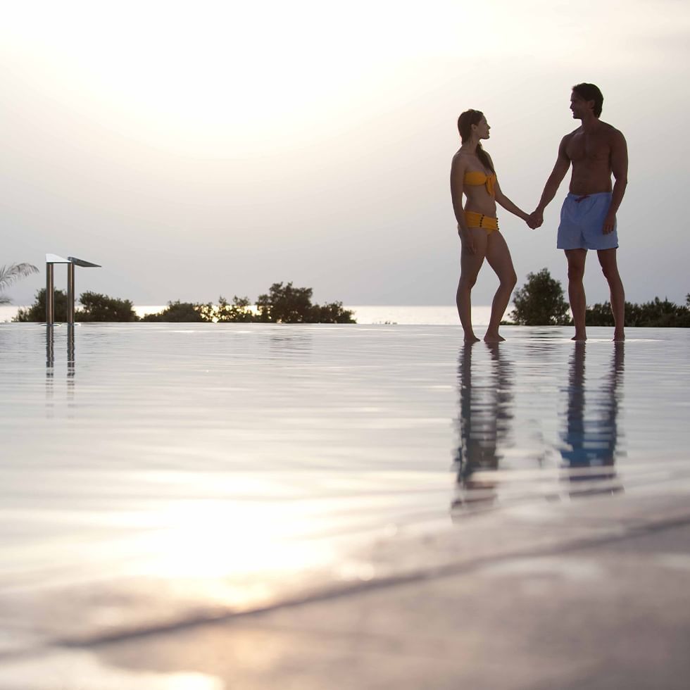 Couple holding hands by the pool at Falkensteiner Hotels