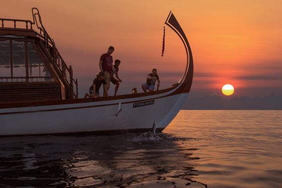 A diverse group of friends on a boat with sunset near Grand Park Kodhipparu, Maldives