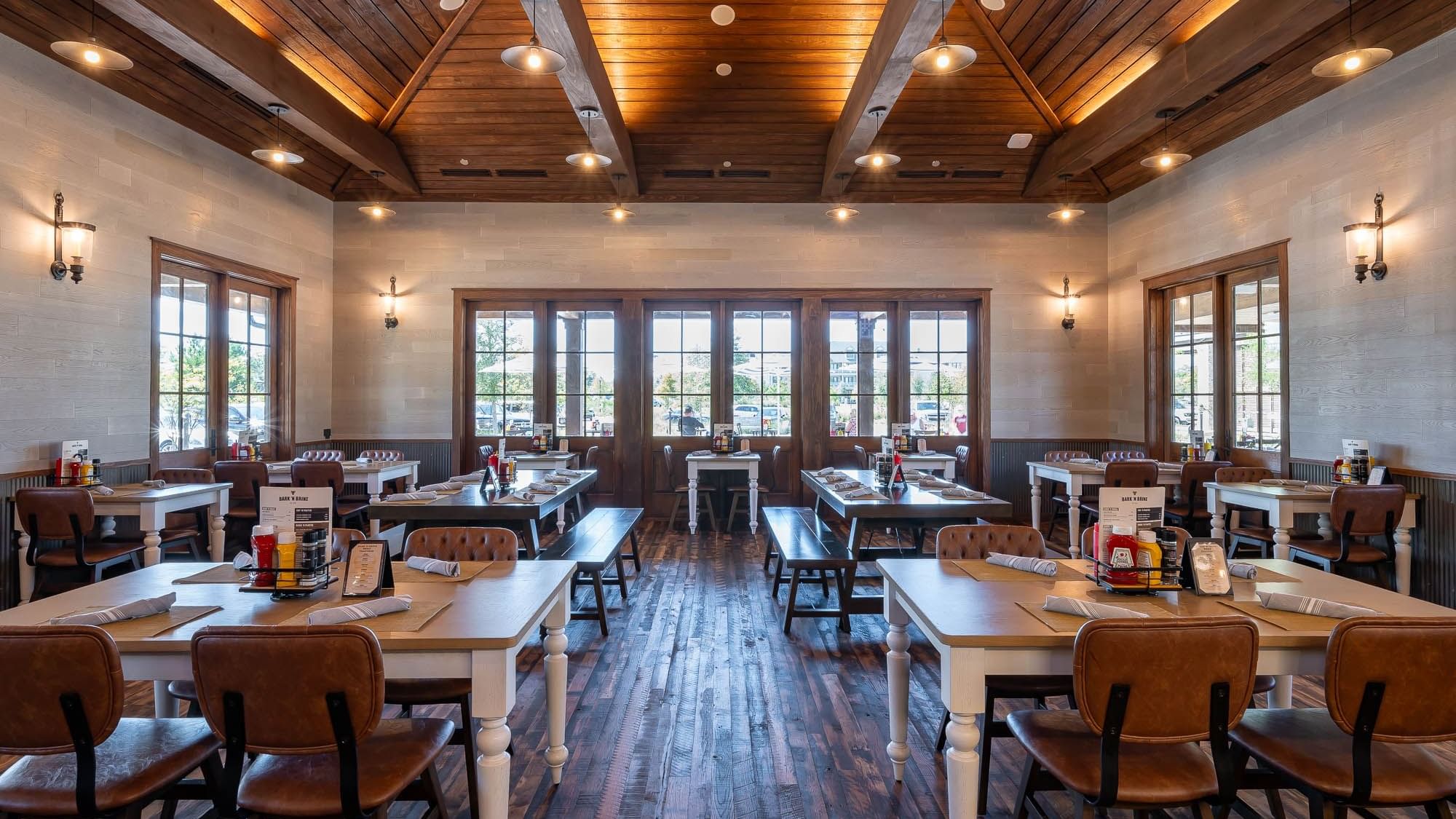 Illuminated interior with dining tables in Bark ‘N Brine at Camp Creek Inn