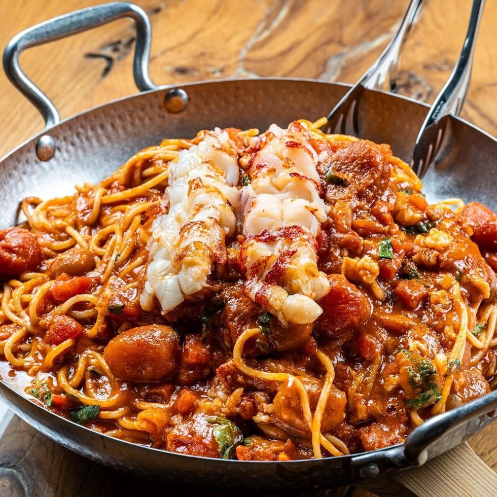 Nudeln mit Meeresfrüchten in würziger Sauce in einer gusseisernen Pfanne.