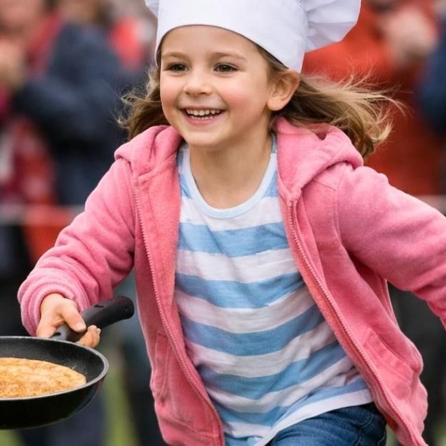 Child running with frying pan in hand at Buckingham's pancake race event