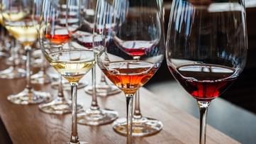 Glasses of various wines lined up on a wooden table for Le Creme Wine Tasting.