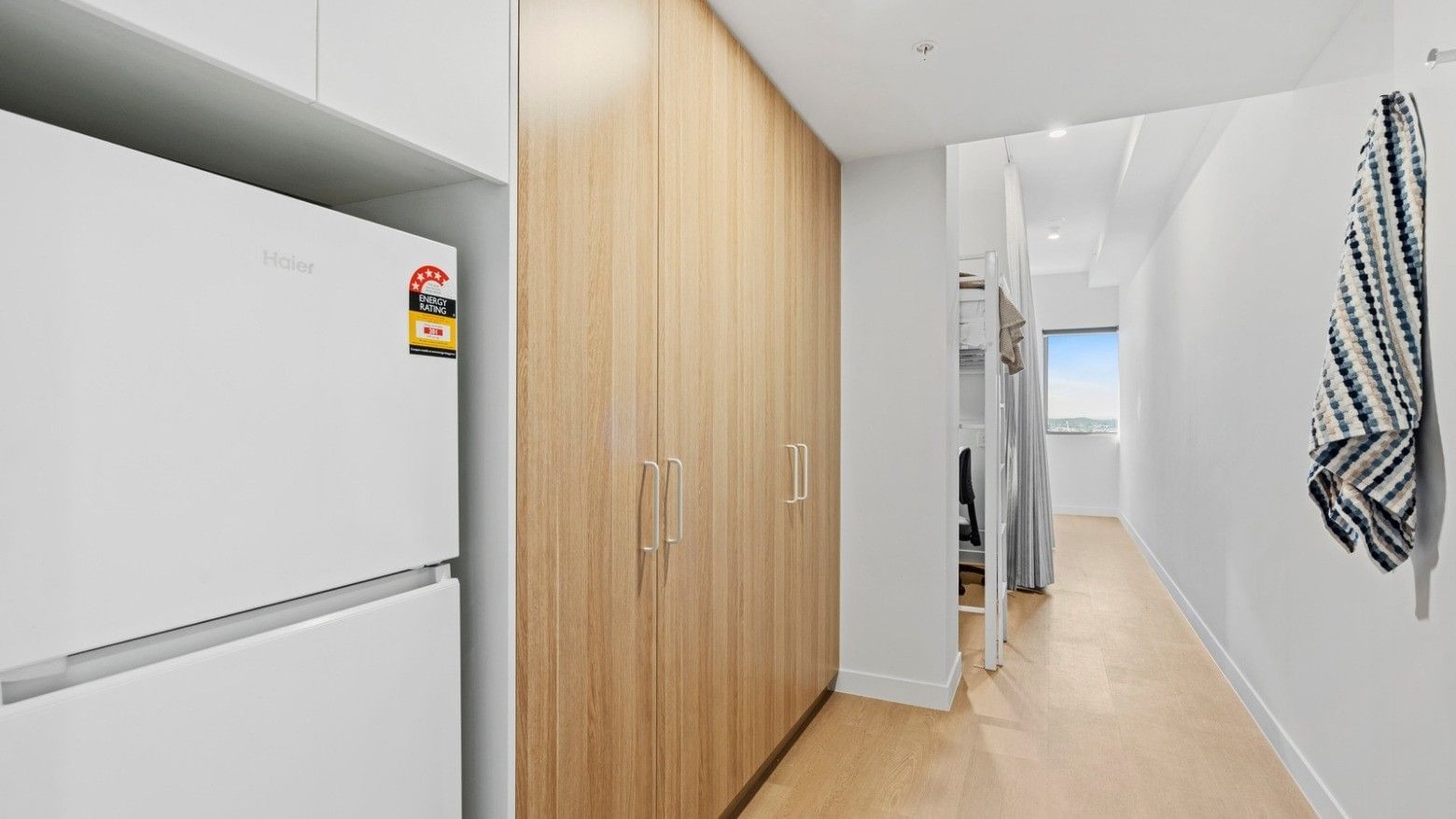 Hallway with white refrigerator, wooden closet, and bunk beds at UniLodge Brisbane City.