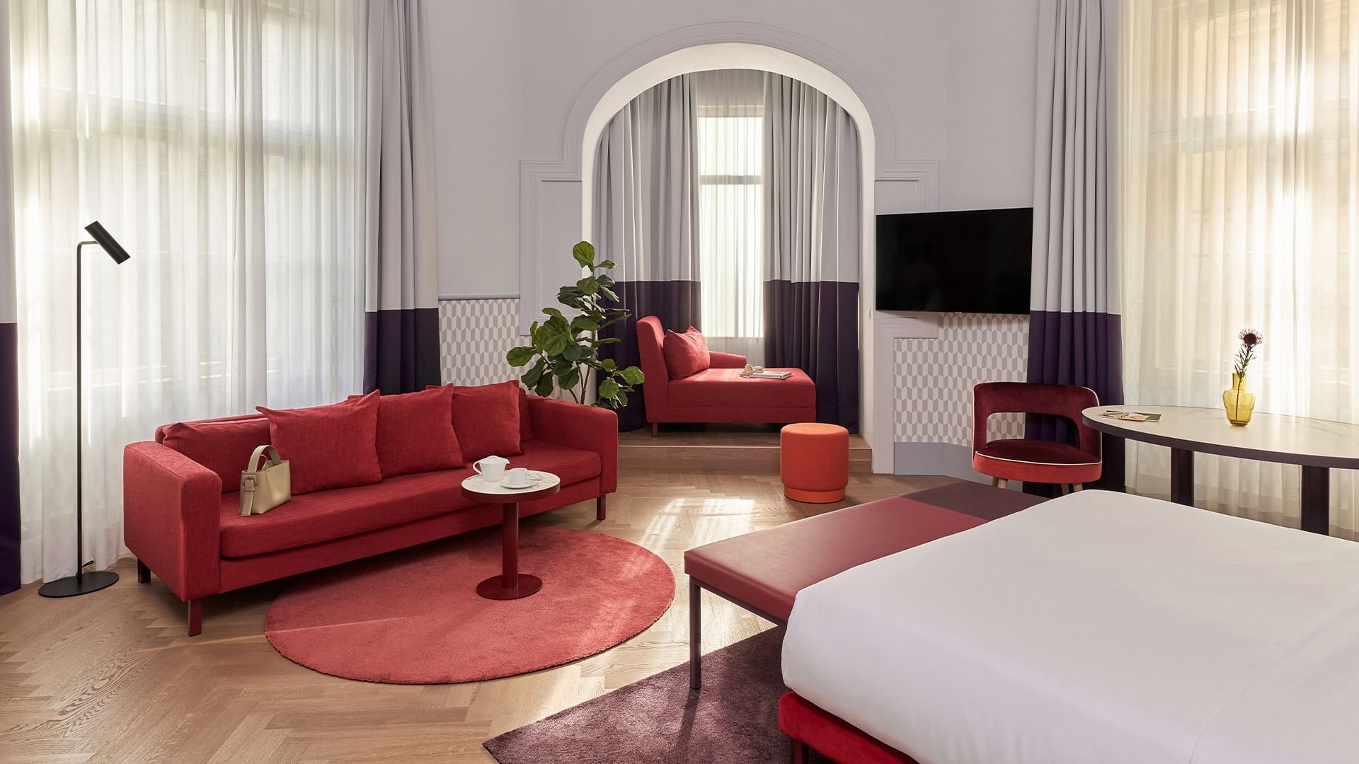 Luxusní Boutique Junior Suite s pohovkou, postelí a TV v Falkensteiner Hotel Prague.