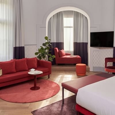Luxusní Boutique Junior Suite s pohovkou, postelí a TV v Falkensteiner Hotel Prague.