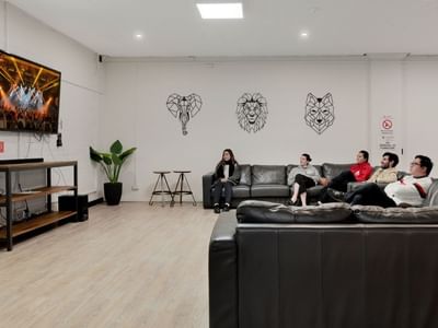 People relaxing on couches in a lounge area with a TV at La Trobe University Menzies College.