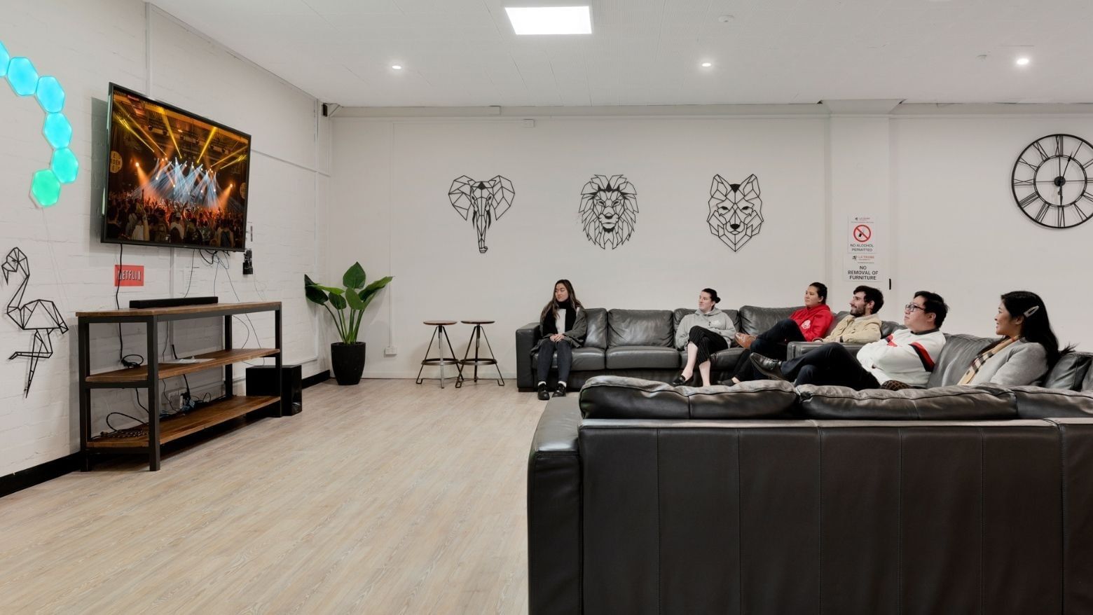 People relaxing on couches in a lounge area with a TV at La Trobe University Menzies College.