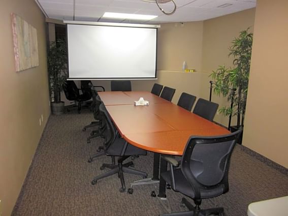 Conference table arranged with screen in meeting room at Fort McMurray Hotels