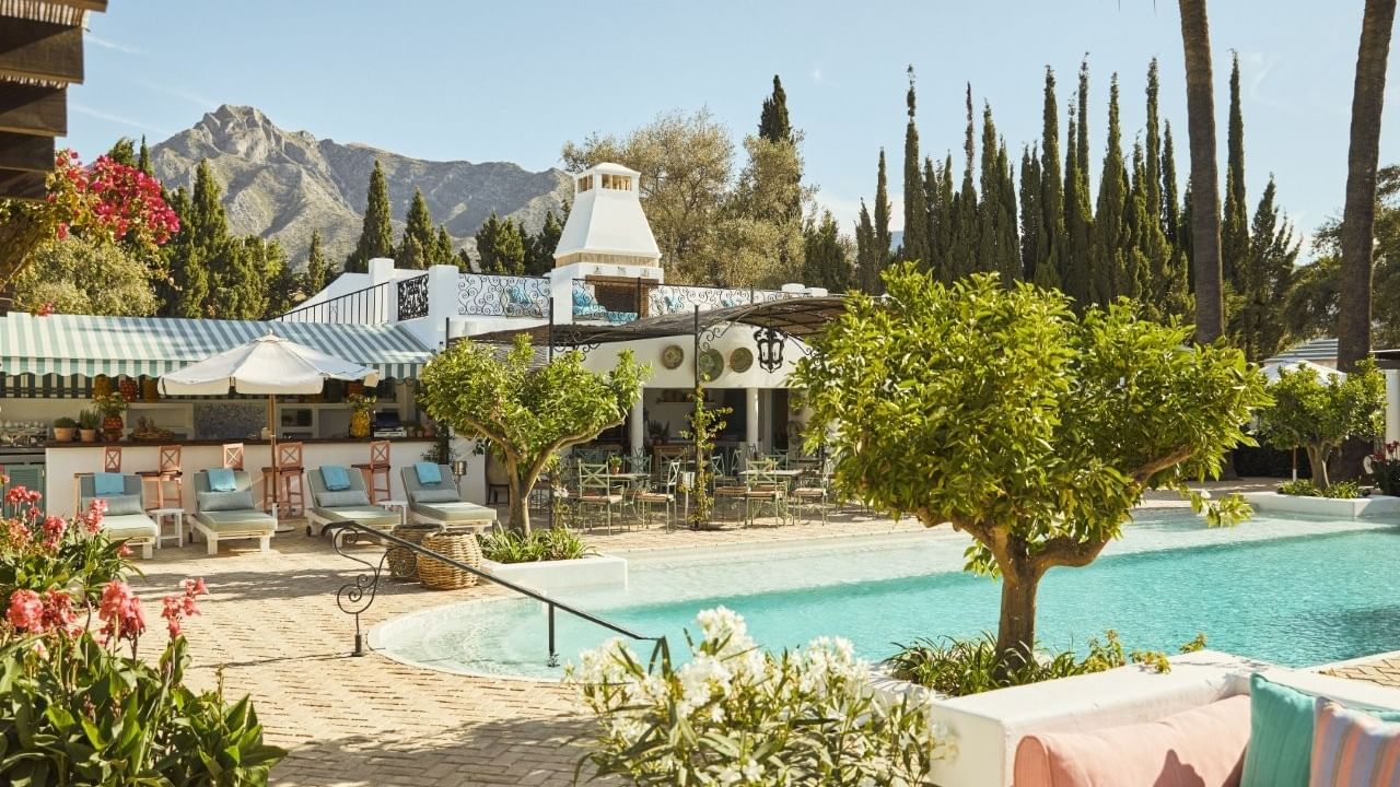 Outdoor dining area with pool and mountain view at El Olivar by Chef Andrés, Marbella Club, Marbella.