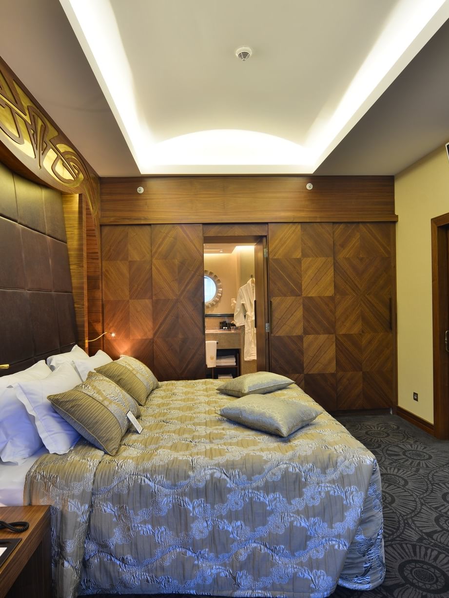Patterned bed by a wood wardrobe under a recessed ceiling light in Ankara Suite with Terrace at Warwick Ankara