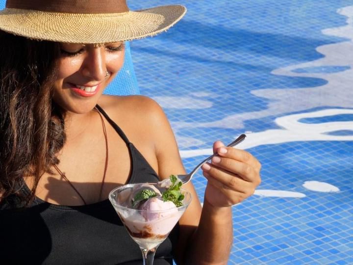 Mujer sonriente con copa de postre al lado de piscina promocionando Apartamento Arrecifes.