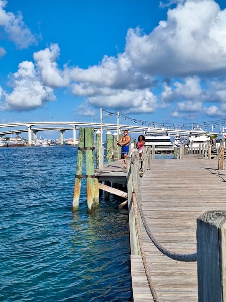 Guests fishing by wooden railings on a long pier under a cloudy sky near Warwick Paradise Island Bahamas